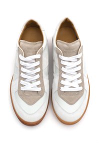 Weiße und beige Sneakers mit einem Obermaterial aus Wildleder und Leder, flachen weißen Schnürsenkeln und einer Sohle aus Gummi. Sie haben eine runde Zehenform und strukturierte Akzente.