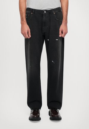 Mustad denim püksid mugava lõikega, millel on kulunud kohad ja nööpidega sulgemine. Kangas tundub pleekinud ja nähtavad õmbluse detailid.