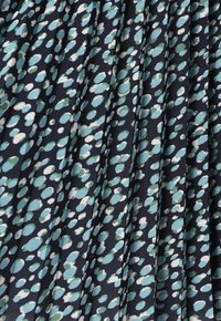 Tissu plissé avec un fond bleu marine et un motif de taches de différentes tailles en turquoise, vert et blanc. Texture douce, matériau léger.