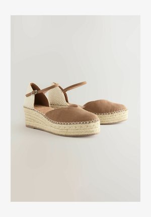 Zapatos de cuña de ante marrón con un talón tejido en beige, tira al tobillo y suela de yute trenzado. Punta redondeada y interior acolchado.