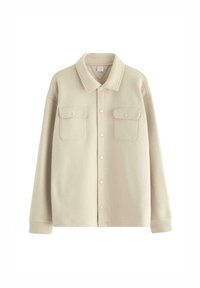 Giacca camicia beige con bottoni realizzata in tessuto morbido, dotata di colletto, due tasche anteriori e chiusura a bottoni sul davanti.