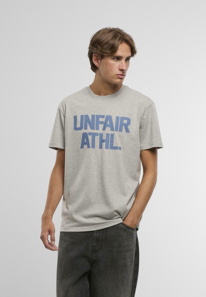 Šedé bavlněné tričko s výrazným modrým nápisem "UNFAIR ATHL." Krátké rukávy, kulatý výstřih, volný střih, hladký materiál.