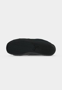 Semelle de basket noire avec motif en diagonale et logo Puma au centre sur fond clair uni.