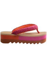 Tongs à plateforme avec une sangle tissée multicolore en orange et rose. Semelle en tan texturé et semelle extérieure striée en marron, rose et corail.