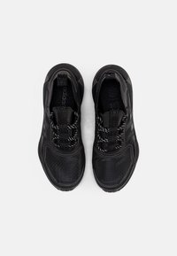 Svarta träningsskor med en texturerad ovandel, mönstrade nätpaneler och reflexsnören. Platta, dämpade sulor för komfort och stöd.