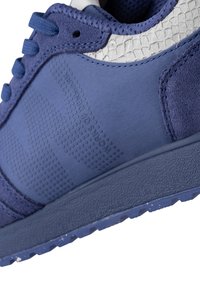 Sneaker navy caratterizzato da un mix di materiali lisci e testurizzati, arricchito da un design a scaglie, suola in gomma e dettagli perforati.