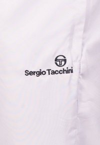 Witte lichtgewicht stof, met een structuur in een diamantpatroon. Bevat een zwart geborduurd logo "Sergio Tacchini" en een cirkelvormige accent.