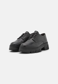 Scarpe stringate in pelle nera con suola in gomma spessa, caratterizzate da una superficie liscia, punte tonde e elementi di design minimalisti.