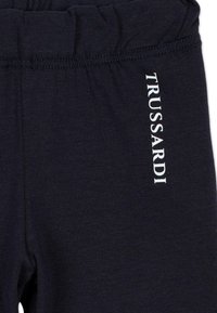 Granatowe bawełniane legginsy z elastycznym pasem. Posiadają pionowo nadrukowane białe logo "TRUSSARDI". Miękka faktura o gładkim wykończeniu.