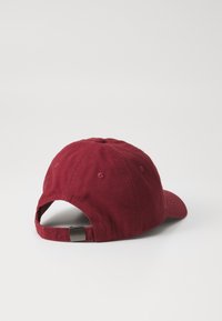 Căciulă de baseball maroon din twill de bumbac cu clemă metalică ajustabilă. Are o margine curbată, ochiuri brodate și un buton superior cusut.