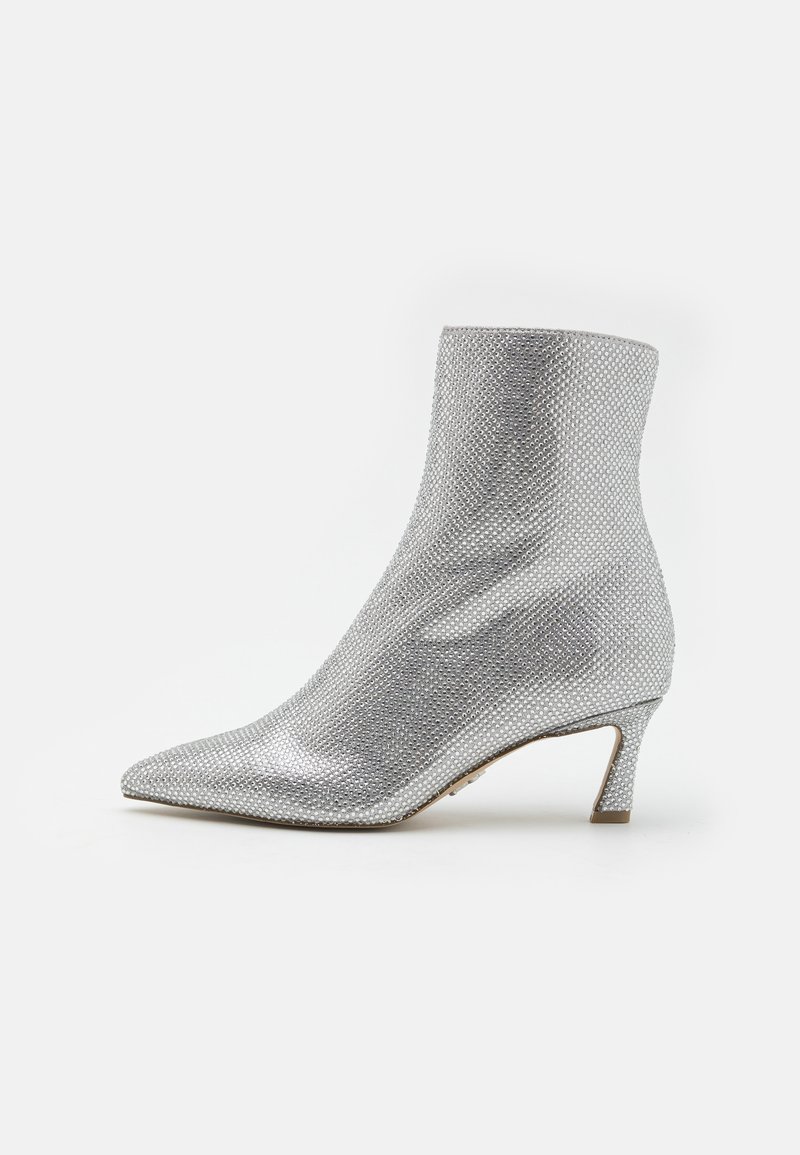 Silver ankle boot with a textured, mesh-like surface, pointed toe, and a low, structured heel. Features a smooth interior lining.
