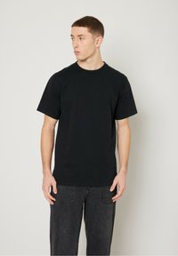 Black cotton short-sleeve t-shirt with a round neckline, paired with dark gray jeans. The fabric is smooth with a simple design.