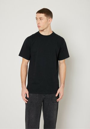 Black cotton short-sleeve t-shirt with a round neckline, paired with dark gray jeans. The fabric is smooth with a simple design.