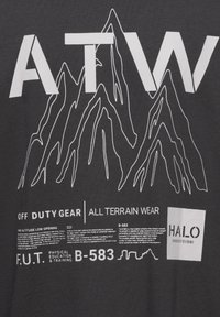 Mørk grå t-shirt med hvid grafisk tryk af bjerge og tekst, herunder "ATW", "OFF DUTY GEAR" og "HALO" med forskellige informationsdetaljer.