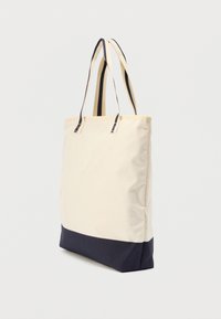 Τσάντα ώμου σε εκρού και ναυτικό μπλε χρώμα, κατασκευασμένη από ανθεκτικό ύφασμα. Διαθέτει δύο ιμάντες για τον ώμο και αντίθετο κάτω πάνελ σε ναυτικό μπλε. Λεία υφή.