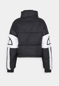 Doudoune noire à col montant, panneaux blancs sur les manches et formes géométriques noires sur les sections blanches, vue de dos.