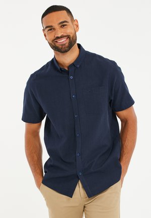 Korte mouwen, marineblauw button-up shirt gemaakt van textuurstof, met een borstzak en contrasterende blauwe knopen.