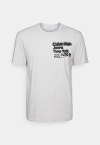 Šedé bavlněné tričko s kulatým výstřihem, krátkými rukávy a černým potiskem: "Calvin Klein Jeans New York 205 W39 St."