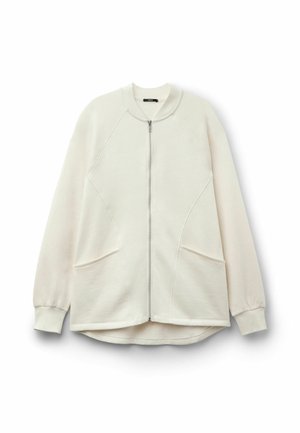 Jasno beżowa bluza zapinana na zamek z raglanowymi rękawami, dwiema przednimi kieszeniami i zaokrąglonym dołem. Wykonana z miękkiego, teksturowanego materiału.