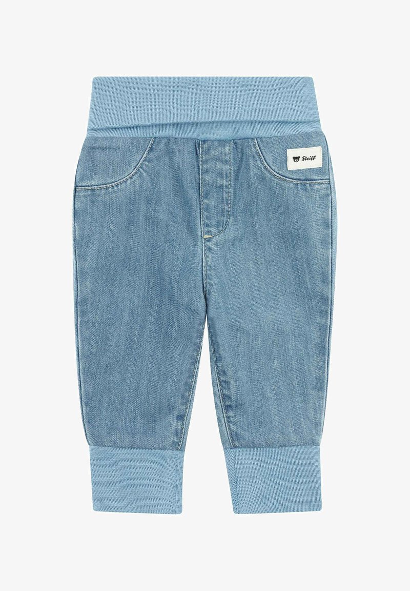 Jean pour bébé bleu clair avec taille et poignets élastiques, poches avant et une petite étiquette de la marque Steiff sur la poche droite.