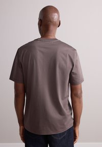 Brown short-sleeve t-shirt made of soft fabric, featuring a crew neckline and a relaxed fit, visible stitching detail on the hem.