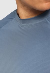 Blaues Sportshirt mit hohem Kragen, aus leichtem, strukturiertem Stoff gefertigt. Verfügt über Raglanärmel und Flachnähte für Komfort.