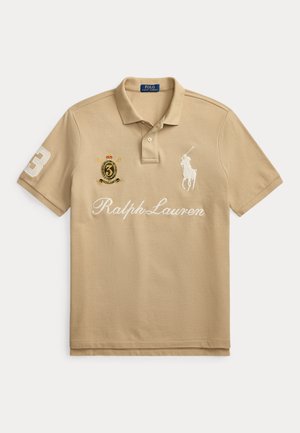 Polo beige avec col, patte de boutonnage, logo joueur de polo brodé, inscription « Ralph Lauren », écusson numéro 3 et emblème de blason.