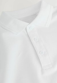 Weißes Poloshirt mit umgeschlagenem Kragen, drei Knöpfen entlang der Knopfleiste und strukturiertem Stoffdetail.