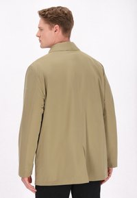 Takki kevyt khaki suoran leikkauksen omaava, jossa on klassinen kaulus, pitkät hihat ja sileä pinta. Ihanteellinen kerroksittain käyttöön.
