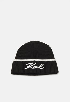 Zwarte gebreide beanie met een witte streep en geborduurd "Karl" logo in cursiefschrift. De textuur is geribbeld voor extra warmte en stijl.