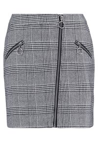 Rutig plyschkjol i svart och vitt, med en knapp framtill och två sidofickor med dragkedja med runda dragkedjehandtag.