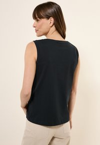 Camiseta sin mangas negra hecha de una tela ligera con un escote redondo. Diseño simple, con un dobladillo recto y sin adornos.