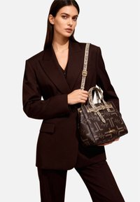 Borsa a tracolla in pelle marrone con motivo geometrico, ferrature dorate e doppio manico. Include una tracolla a contrasto con dettagli con logo.