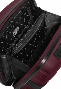 Bordeaux rugzak interieur met meerdere compartimenten, zwarte voering met herhalend logo-patroon, soepele ritsen en gestructureerde buitenkant.