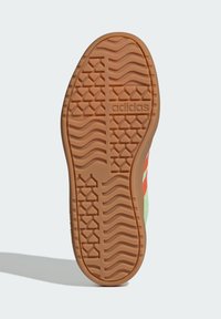 Donji dio cipela s reljefnim uzorkom od smeđeg gume s Adidas logom. Živi zeleni gornji dio s narančastim akcentima. Uzorak protiv klizanja.