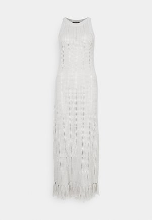 Vestido de croché blanco, largo y sin mangas, con rayas verticales y detalles de flecos en el dobladillo para textura y movimiento.
