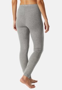 Grijze legging gemaakt van zacht, rekbaar materiaal met een aansluitend ontwerp, voorzien van een elastische tailleband en taps toelopende benen die eindigen bij de enkels.