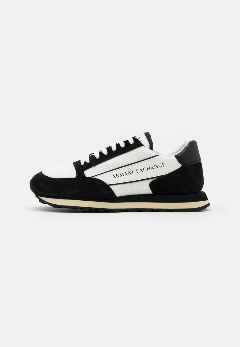 Czarne zamszowe sneakersy z białym materiałem, z fakturowanym językiem, czarnymi sznurówkami, charakterystycznym brandingiem i kremową podeszwą.