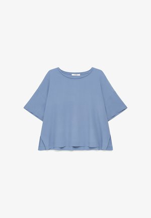 Blouse femme bleu clair, coupe ample, manches courtes, encolure ronde et ourlet arrière légèrement plus long.