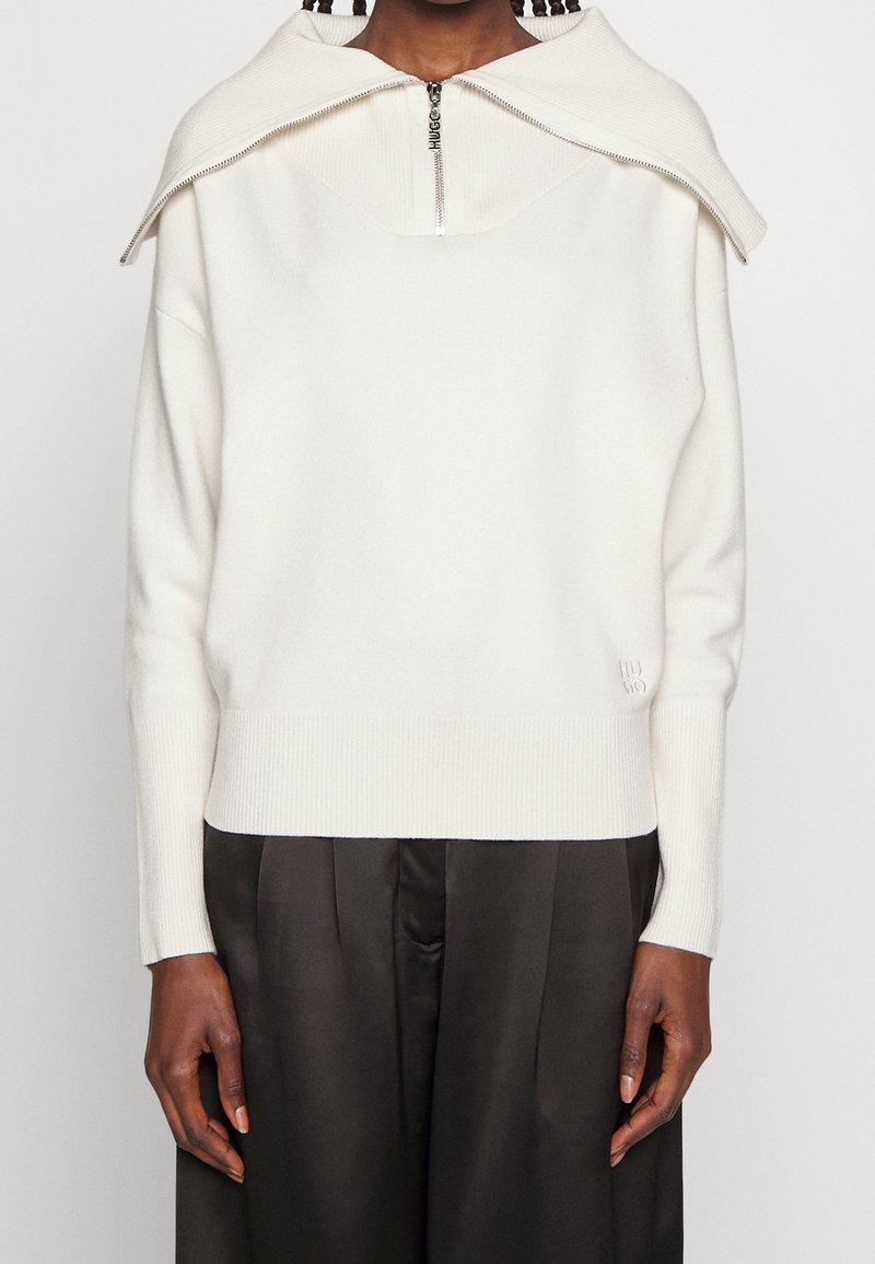 Witte gebreide trui met een brede, opgevouwen kraag en een halve ritssluiting; geribbelde manchetten en zoom; minimale logodetail aan de zijkant.
