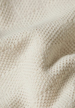 Close-up van crèmewit gebreide stof met zachte, gestructureerde steken en zachte plooien.