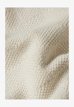 Close-up van crèmewit gebreide stof met zachte, gestructureerde steken en zachte plooien.