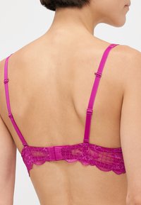 Pink lace bra with adjustable straps, featuring a floral pattern and scalloped edges, showcasing a smooth back design.
