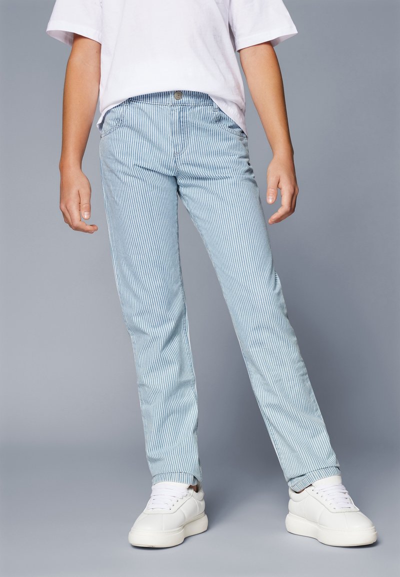 Vaalean siniset raidoitetut housut, joissa on slim fit -leikkaus, valmistettu pehmeästä kankaasta. Ominaisuuksiin kuuluvat etutaskut ja nappikiinnitys, yhdistettynä valkoisiin lenkkareihin.