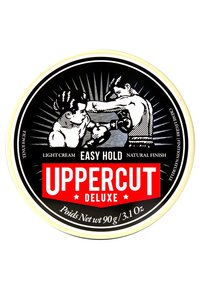 Rund sort tin med hvide og røde detaljer. Har vintage boksning kunstværk og tekst: "UPPERCUT DELUXE" samt produktinformation på engelsk og fransk.