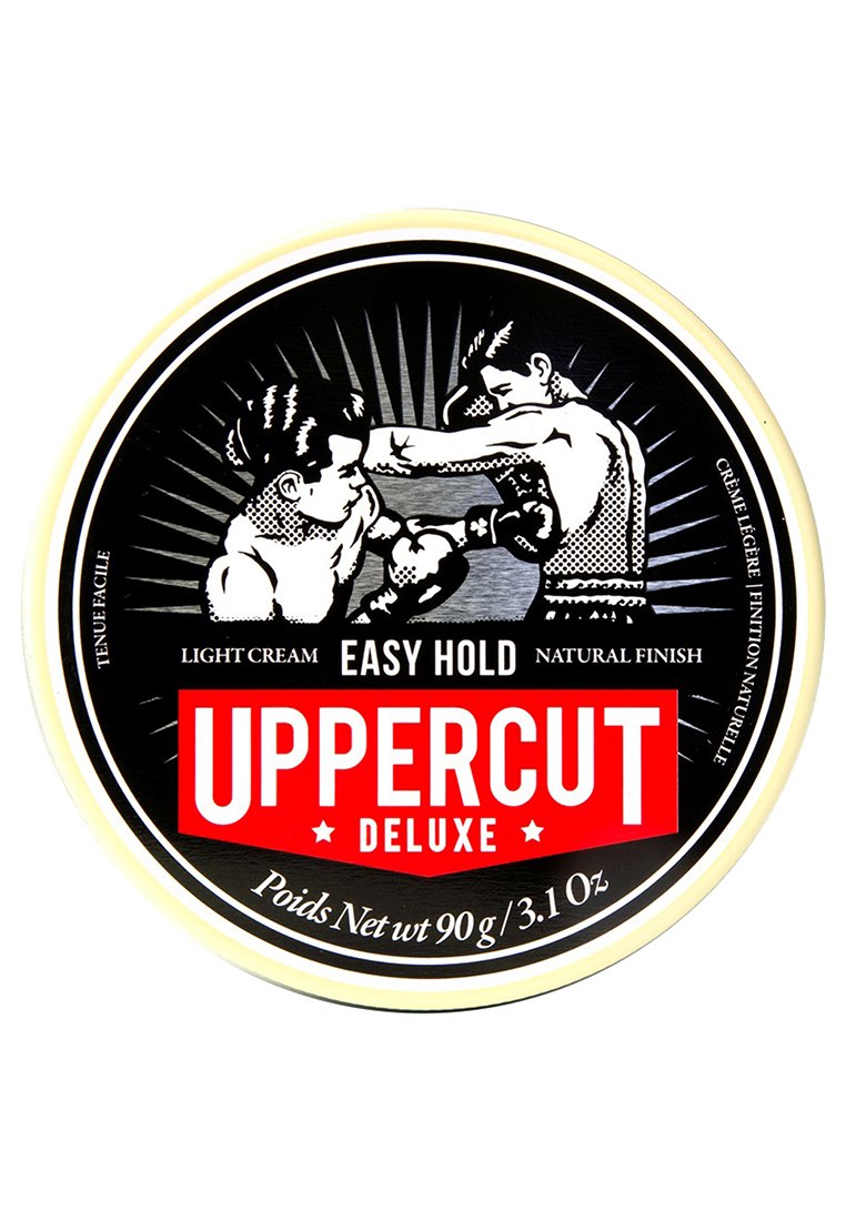 Rund sort tin med hvide og røde detaljer. Har vintage boksning kunstværk og tekst: "UPPERCUT DELUXE" samt produktinformation på engelsk og fransk.