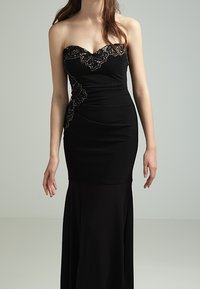 Svart axelbandslös aftonklänning med utsmyckad spetsdetalj vid kroppsdelen, figursydd silhuett och flödande kjol som sträcker sig ner till golvet.