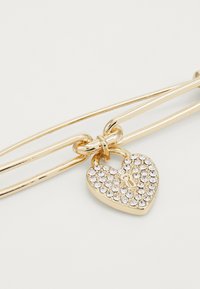 Gold-tone bracelet featuring a heart-shaped padlock charm with a crystal embellishment and a keyhole design, smooth metal texture.