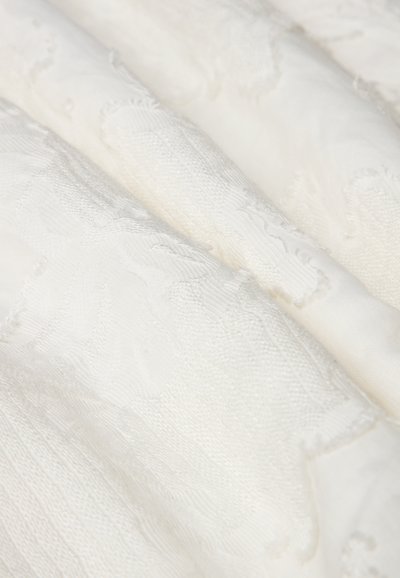 Tessuto bianco testurizzato con motivi sottili e intrecci di superficie variabili, con una finitura morbida e liscia e una leggera lucentezza.
