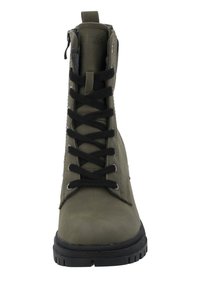 Bota de combate verde oliva con cordones negros, suela de goma y cremallera lateral. Presenta ojales reforzados y un upper texturizado para mejor agarre.